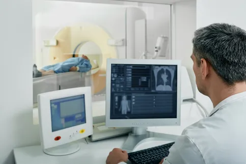 Doctor radiologist running CT scan for patient's body lungs from control room. Computed Tomography