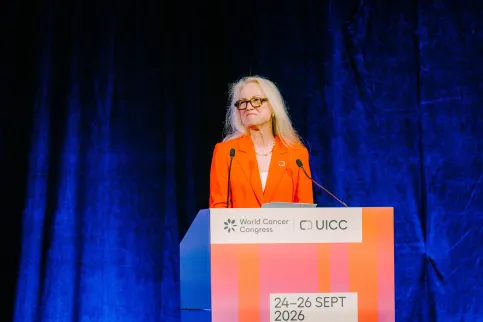 Woman with blond hair and wearing orange suit standing at a podium