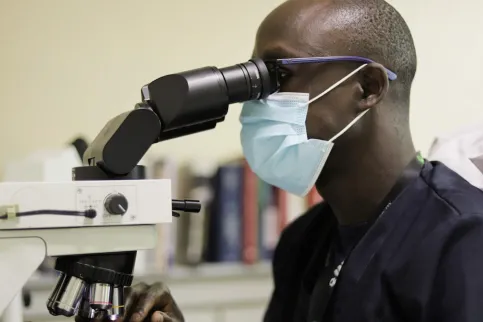 Man looking into a microscope, pathology unit at the Aga Khan University Hospital in Kenya