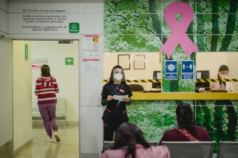 Health care worker at FUCAM in Mexico, with large pink ribbon in the background symbolising Breast Cancer Awareness Month