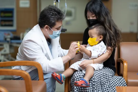 Doctor speaking to a mother holding a baby wearing masks 
