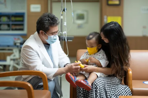 Doctor speaking to a woman and her child. (C) National Cancer Center - Korea (NCCK)