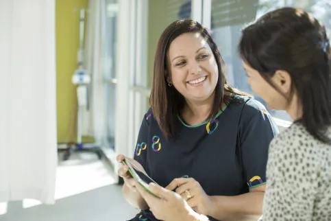 A smiling medical practitioner provides instructions to a student