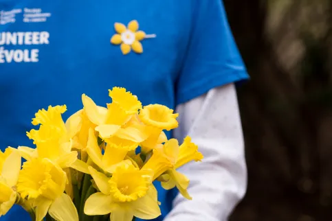 Cropped person holding yellow flowers that symbolise the Canadian Cancer Society.