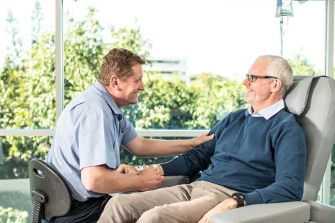 Male nurse sitting with patient on intravenous feed
