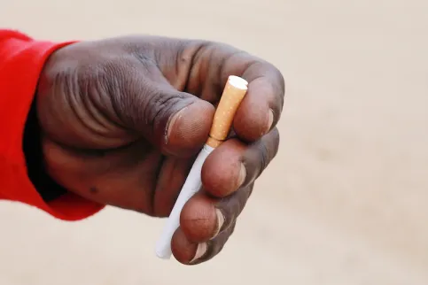 Hand of African man holding a cigarette, emphasising the need for tobacco control