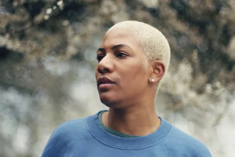 Black woman with blue sweater looking out into the distance