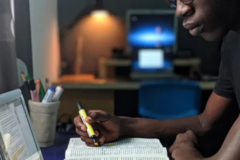 A man consulting a book and iPad, symbolising the value of online learning