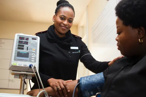 Black healthcare worker checking a Black women's blood pressure