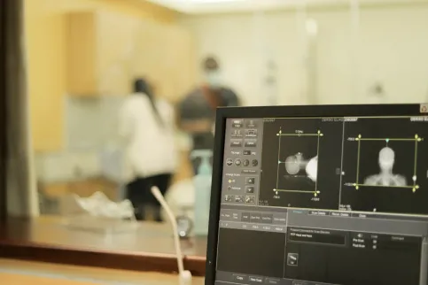 Close up of a image scan of a cancer patient undergoing an imaging examination (MRI), with health practitioners in the background