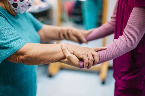 Patient and caregiver holding hands, close-up.