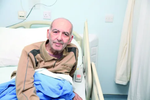 Male patient sitting up in his medical bed at the King Hussein Cancer Foundation in Jordan