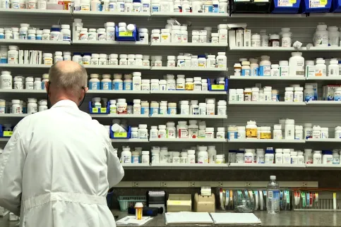 Pharmacist in front of medicine shelf