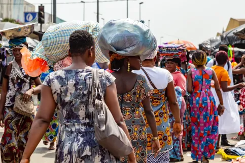 Image from behind of women in Africa walking in a market, some carrying parcels on their heads