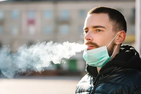 Man smoking with medical mask on his chin