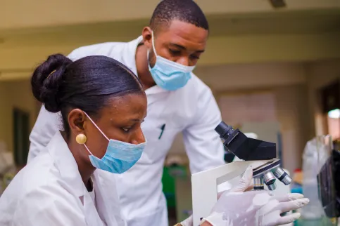 African female and male health care researchers working in life science laboratory, preparing and analysing microscope slides in a research lab