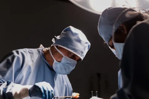 Image shows surgeon at work, emphasising the importance of comprehensive healthcare on in cancer control
