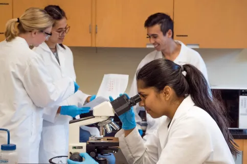 Woman looking through a microscope in a lab