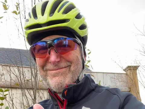 Cancer patient wearing a yellow bike helmet giving the thumb's up