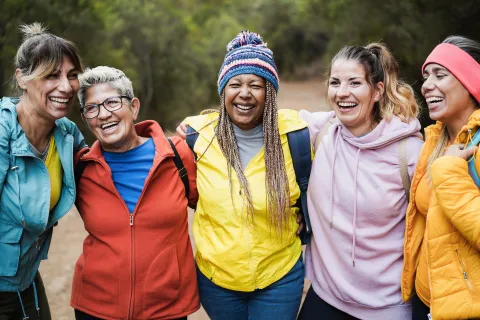 A group of women of different ages and ethnicities with arms over shoulders and smiling