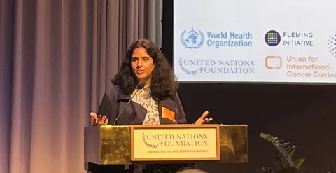 A British-Indian woman, Dr Sonali Johnson of UICC, delivers a speech at a podium with UN logos on a backdrop behind her