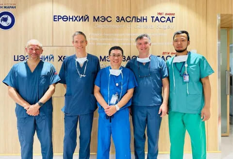 Five male doctors smiling to the camera