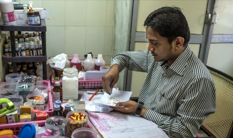 Man sitting at a desk weighing out medication
