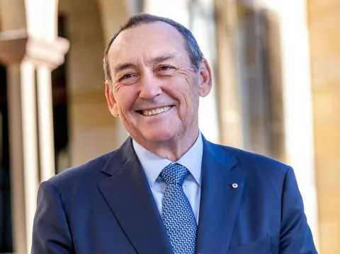 Headshot of Prof. Jeff Dunn, AO, President of UICC (2022-2024), in blue suit and tie, clasping hands in front of him