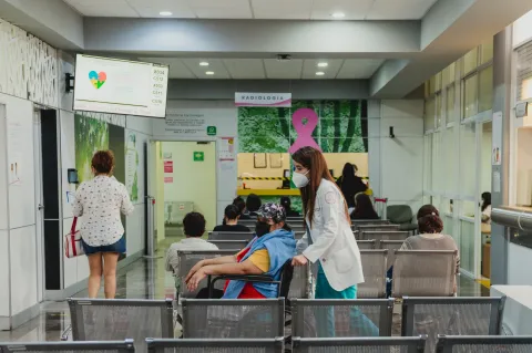 Healthworker pushing a patient in a wheelchair in hospital area