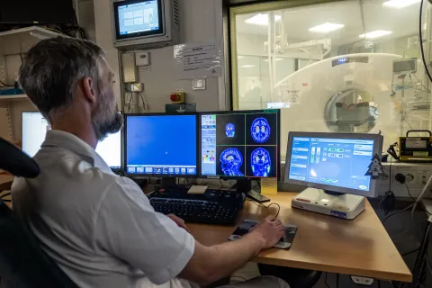 Middle age white male in white shirt looking at cancer screening images on computer screens