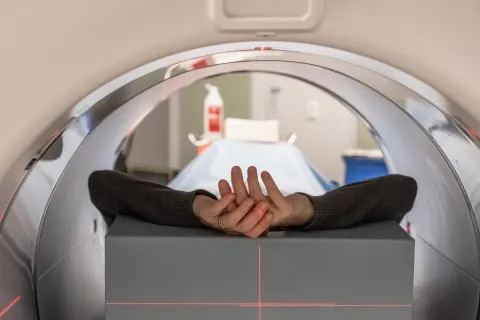 Hands of person on a examining bed in a screening machine