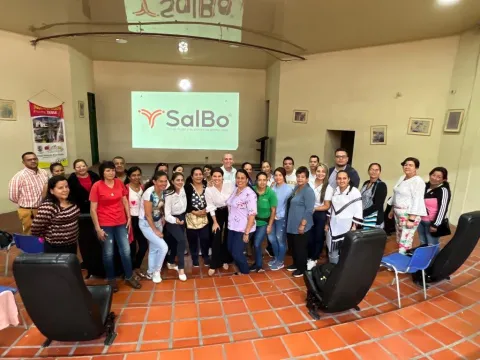 Group of people in a large room in front a screen featuring the word "SalBo" a cancer organisation