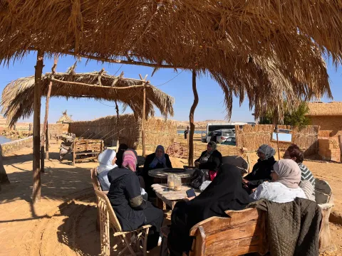 Group of Middle Eastern women sitting at a table in a desert village