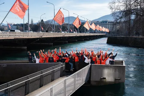 Diverse group of people in World Cancer Day branded hoodies posing outdoors in front a bridge lined with World Cancer Day flags