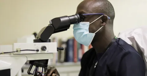 World Cancer Research Day on 24 September celebrates the power of partnerships. A collaborative research culture is therefore essential to allow more people to be diagnosed earlier and treated more effectively, with a better quality of life at every stage of the disease – and after. Man looking into a microscope, pathology unit at the Aga Khan University Hospital in Kenya