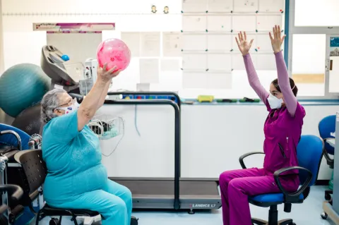 Older patient doing physical exercise with a healthworker