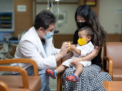 Doctor speaking to a mother holding a baby wearing masks 