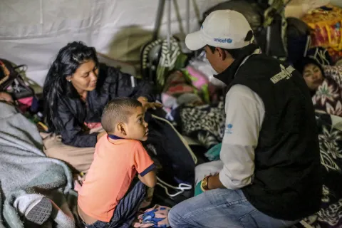 Documented Venezuelan migrants have the same access to basic cancer services as Colombians through the national health scheme, but the nature of the cancer burden among the migrant population remains unknown. UNICEF staff member assisting a mother and child in a migrant camp for Venezuelans leaving the country. UNICEF launched a regional response in 2018 to support children and families from Venezuela, as well as children in host communities. Photo ©UNICEF/2018/Moreno