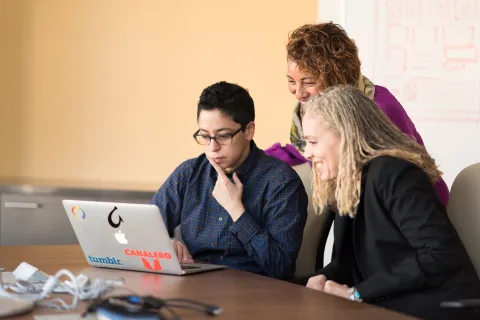 3 Persons looking at a laptop