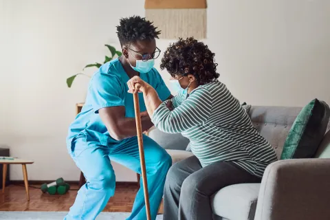 Persons with disabilities often encounter a number of barriers to accessing the medical care they need, including stigma, assumptions about their health, or medical devices that cannot accommodate their disability. A caregiver helping a woman with impaired mobility to rise from a chair