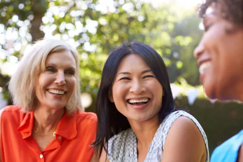 three women laughing in a park