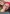 Black woman with red headscarf and wearing headphones smiles to the camera