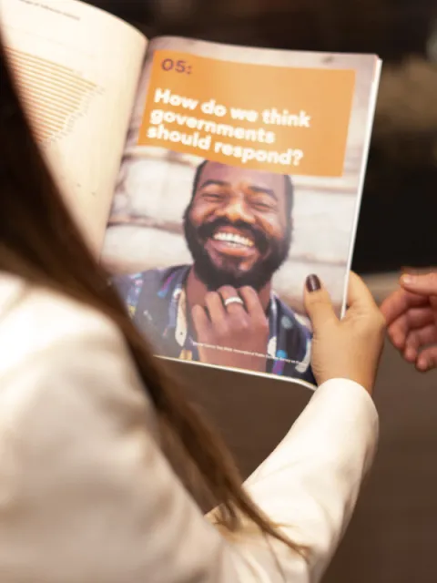 Woman holding a publication open with the title "How do we think the governments should respond?"