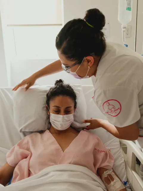 A nurse helps a patient at the hospital - both are wearing a mask