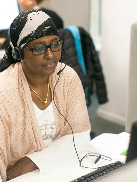 woman with headset looking at her screen computer