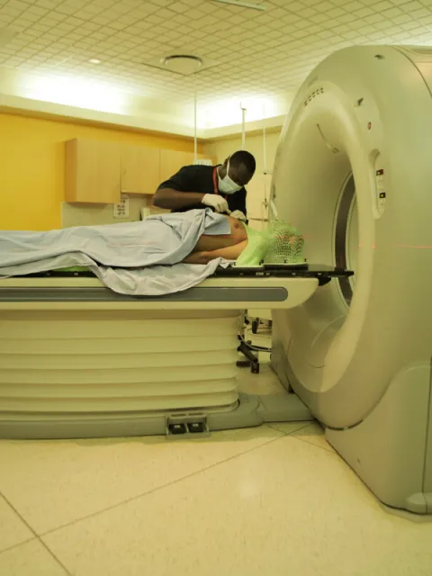 Medical worker assisting a patient to lie down before entering a MRI scanning machine