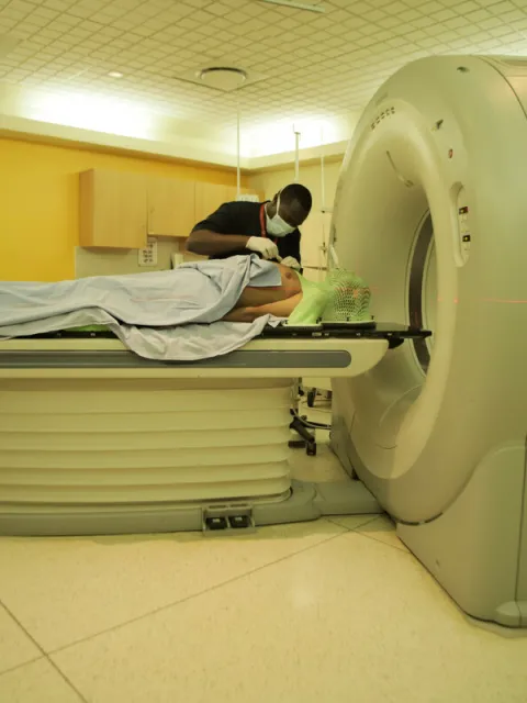 Medical worker assisting a patient to lie down before entering a MRI scanning machine