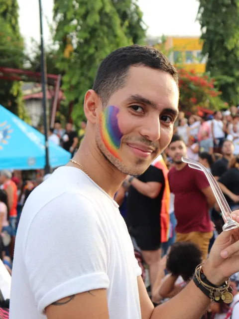 Man with with Pride rainbow on his cheek at a rally