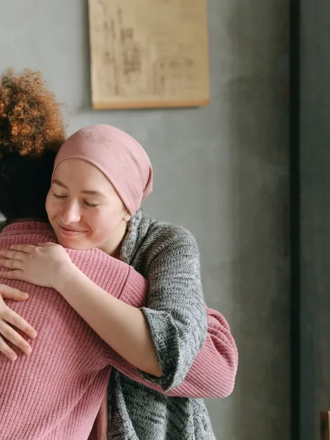 A woman embracing another woman wearing a headscarf