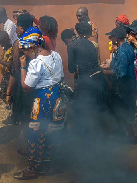 Crowd of men and women with hands to their faces as they walk through a heavily polluted area marked by black smoke